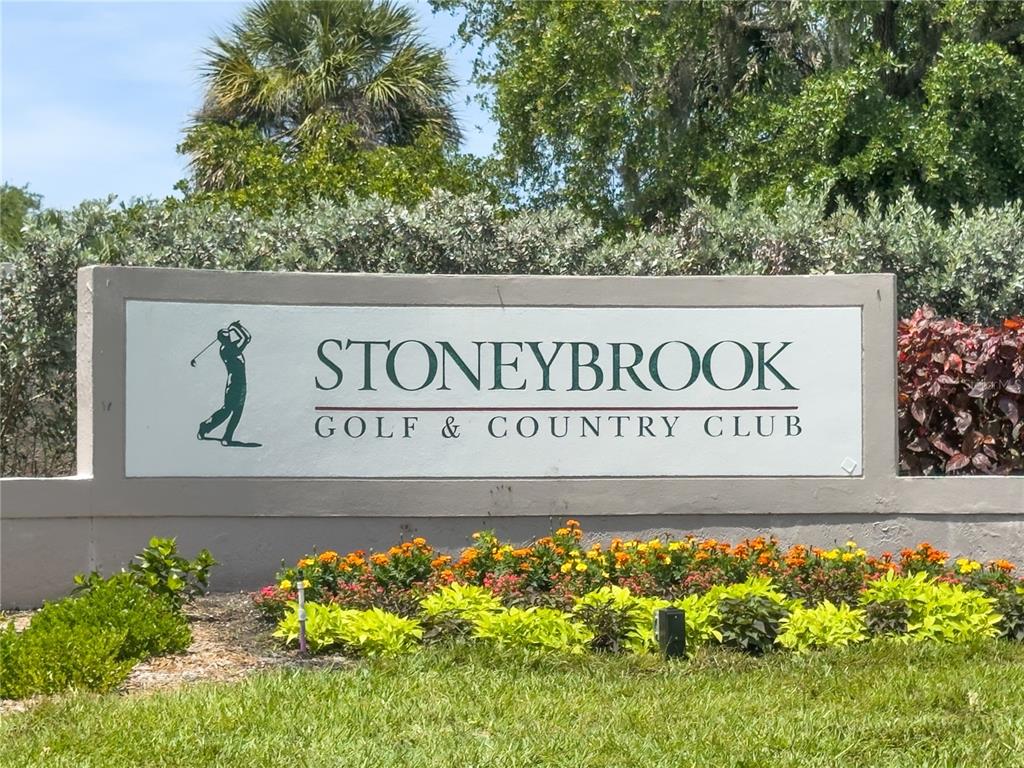A sign for Stoneybrook Golf & Country Club stands in front of landscaping and trees — 9320 CLUBSIDE CIRCLE UNIT 2201, SARASOTA, FL