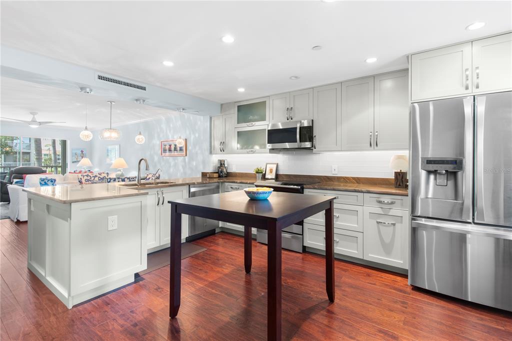 A kitchen features light gray cabinets, stainless steel appliances, a dark wood island, and hardwood floors — 9320 CLUBSIDE CIRCLE UNIT 2201, SARASOTA, FL