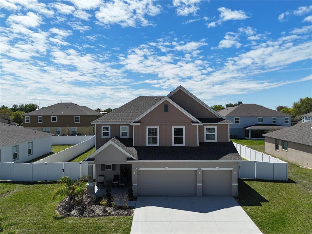 An aerial view of a two-story suburban house with a three-car garage and white fencing — 923 FIELDSTONE WAY, HAINES CITY, FL