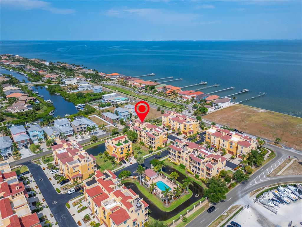 An aerial view shows a waterfront residential complex with a pool and boat docks — 6407 MAYRA SHORES LANE, APOLLO BEACH, FL