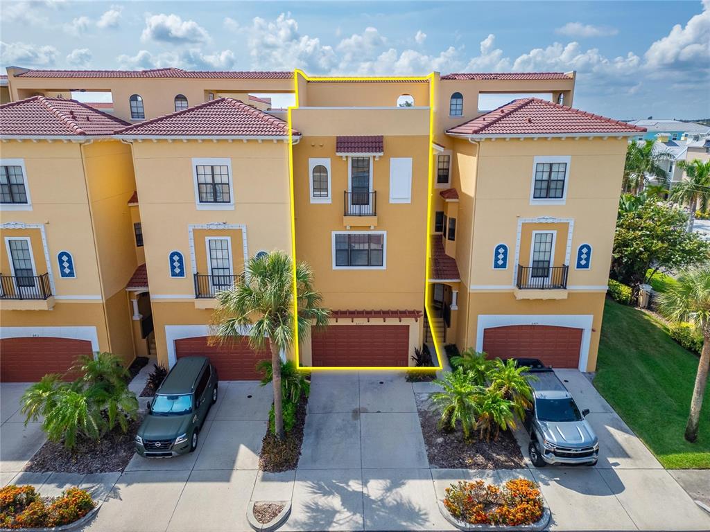 An aerial view shows a three-story yellow townhouse with a garage and tiled roof — 6407 MAYRA SHORES LANE, APOLLO BEACH, FL