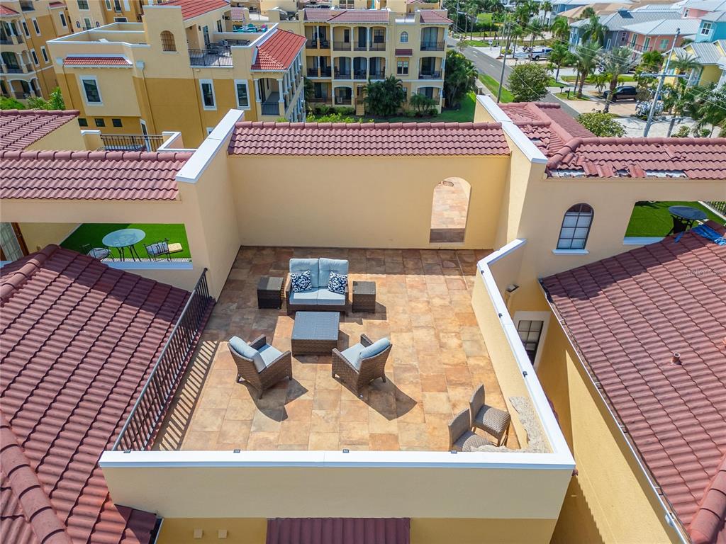 An elevated outdoor rooftop terrace features tiled flooring, patio furniture, and surrounding stucco walls — 6407 MAYRA SHORES LANE, APOLLO BEACH, FL