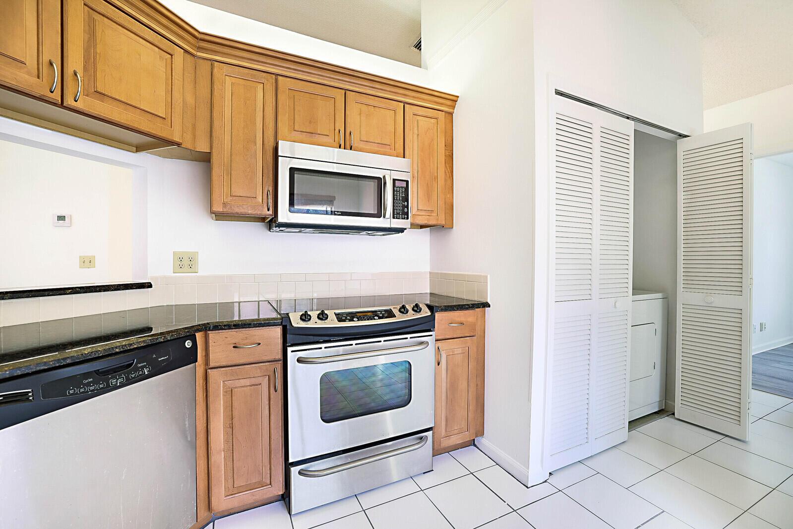 A kitchen with light wood cabinets, stainless steel appliances, and white tiled flooring — 9 Vía De Casas Sur # 203, Boynton Beach FL 33426, BOYNTON BEACH, FL