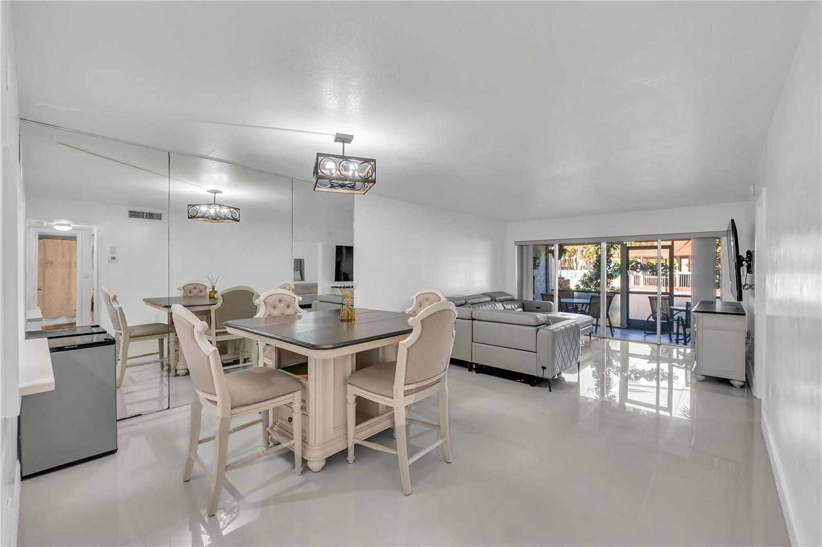 A dining area with a square table and chairs sits before a large mirrored wall — 3920 Inverrary Boulevard # C, Lauderhill FL 33319, LAUDERHILL, FL