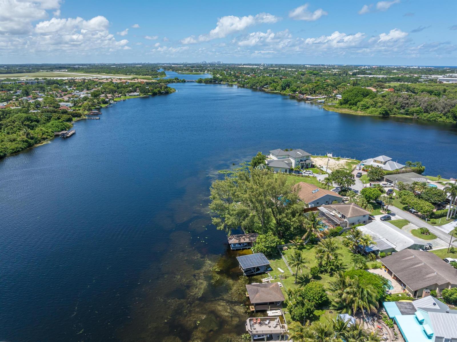 An aerial view shows a residential neighborhood situated along a large, calm river — 6563 Paul Mar Drive, Lake Worth FL 33462, LAKE WORTH, FL