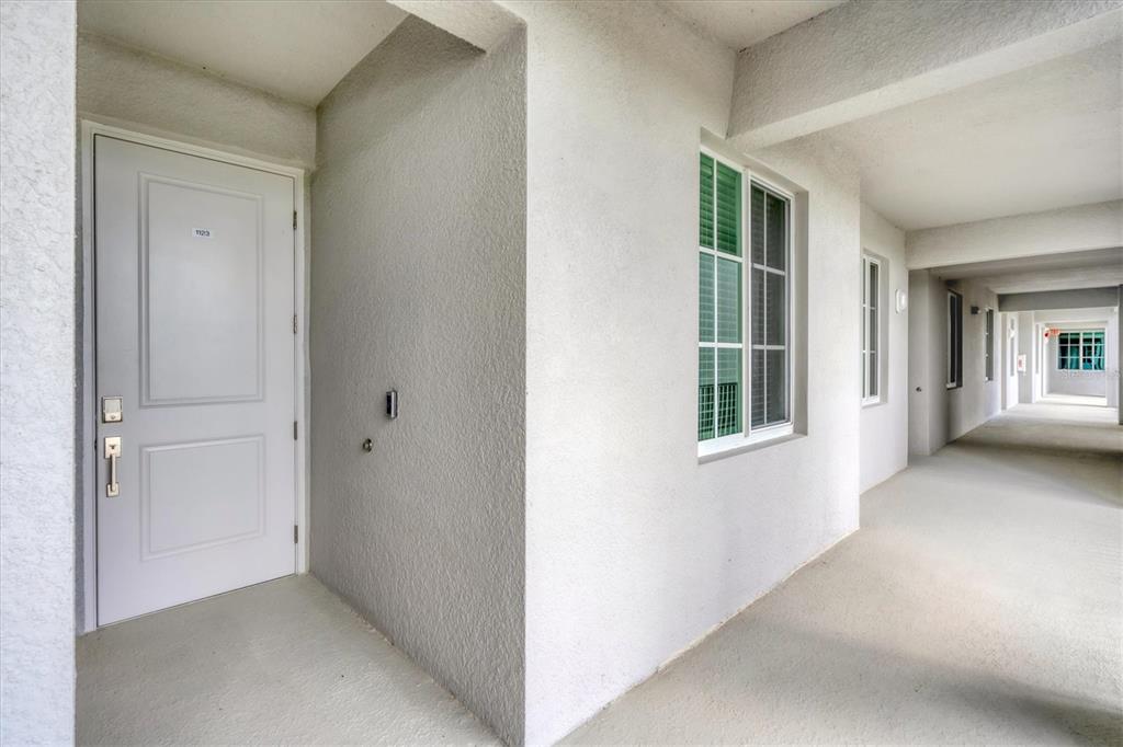 A white door with the number 1123 leads to an outdoor hallway with stucco walls — 14161 HERITAGE LANDING BOULEVARD UNIT 1123, PUNTA GORDA, FL