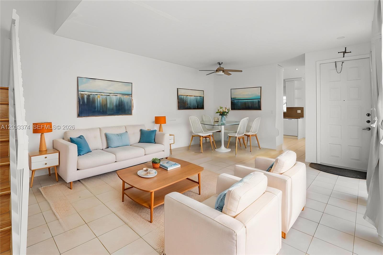 A bright living and dining area features white tile floors, neutral furniture, and wall art — 1521 Seagrape Way, Hollywood FL 33019, HOLLYWOOD, FL