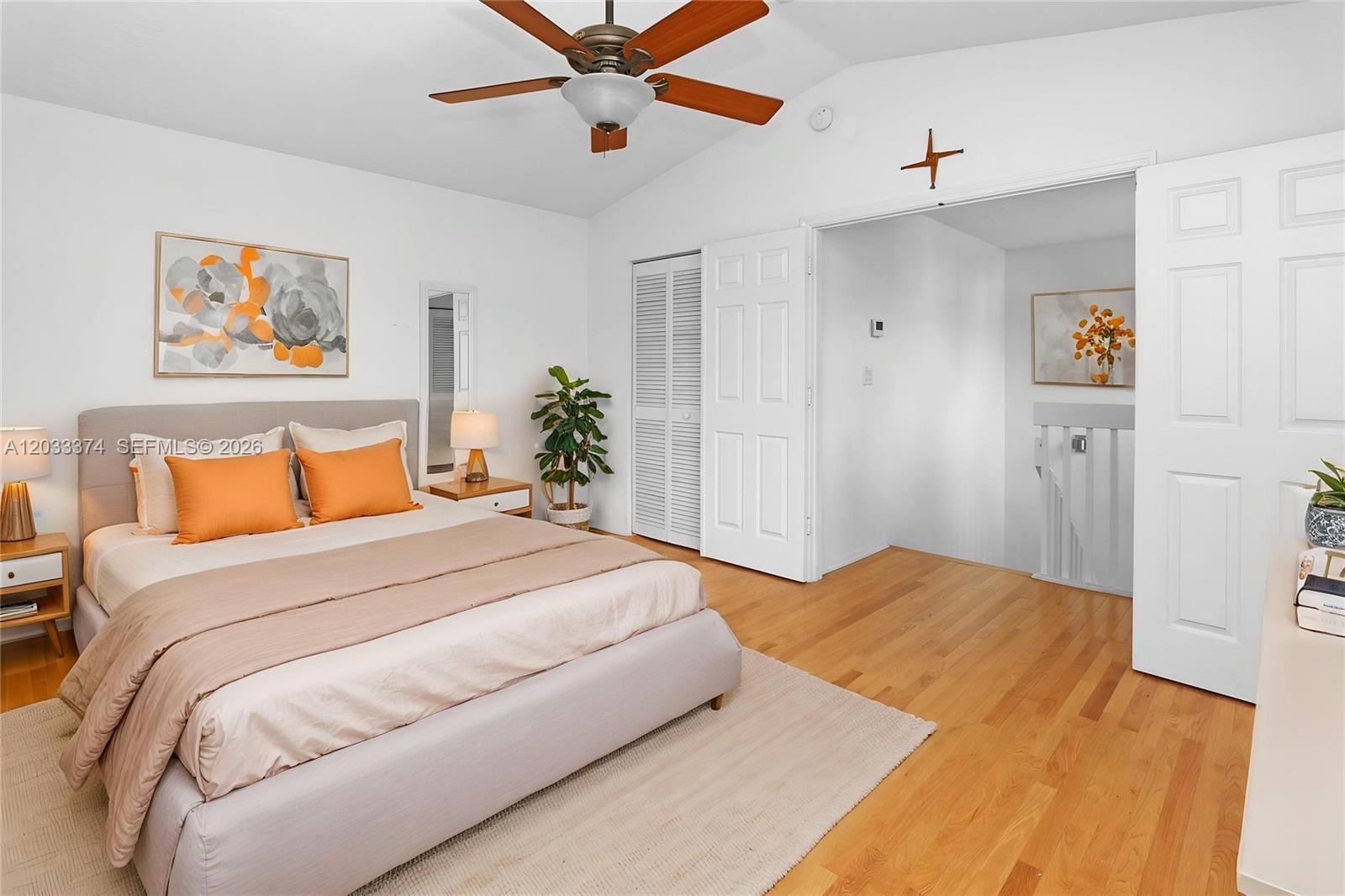 A bedroom features a bed with orange pillows, hardwood floors, and a ceiling fan — 1521 Seagrape Way, Hollywood FL 33019, HOLLYWOOD, FL