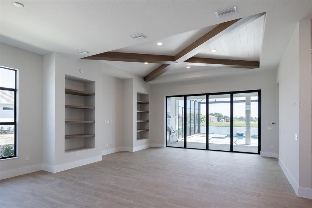 A living room features a coffered ceiling with wood beams, built-in shelving, and sliding glass doors — 312 BLUE PEARL CT., SARASOTA, FL