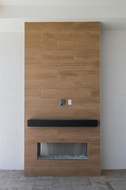 A modern fireplace with a wood-look tile surround and a black mantel on a patio — 312 BLUE PEARL CT., SARASOTA, FL