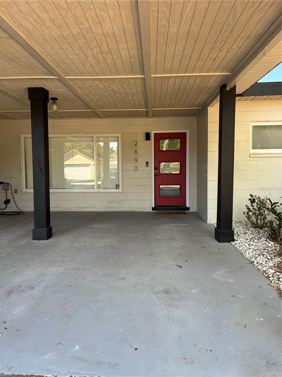 A covered carport leads to a red front door with three horizontal glass panels — 2690 SMOKEY LANE, TITUSVILLE, FL