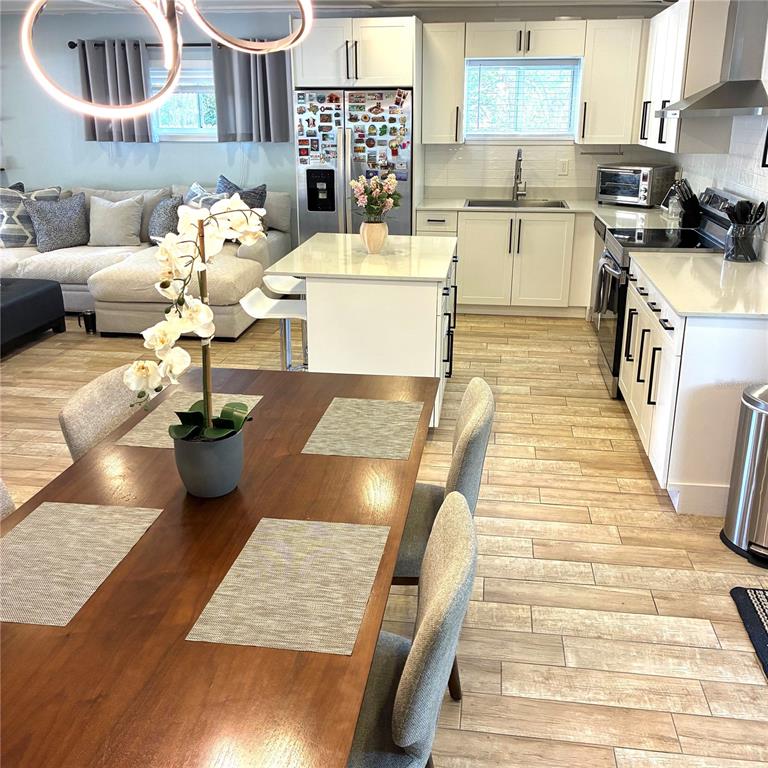 An open-concept kitchen and dining area features white cabinets, a central island, and wood-look flooring — 2690 SMOKEY LANE, TITUSVILLE, FL