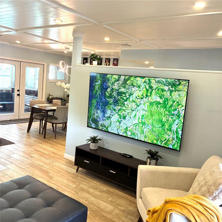 A living room features a wall-mounted television above a dark media console and tile flooring — 2690 SMOKEY LANE, TITUSVILLE, FL