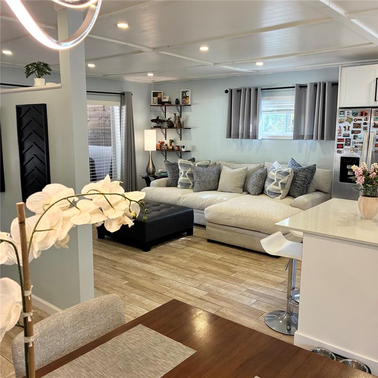A living room with a sectional sofa, ottoman, and open kitchen area with tile flooring — 2690 SMOKEY LANE, TITUSVILLE, FL