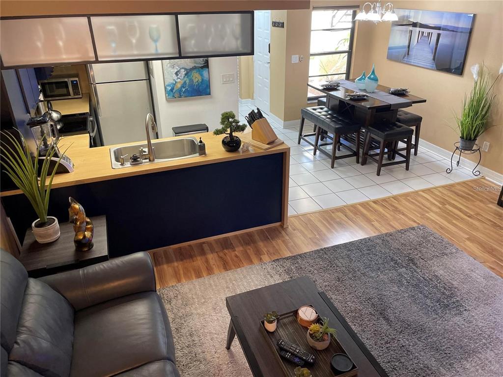 An open-concept living room and kitchen area with dark cabinetry, wood flooring, and dining space — 2571 CYPRUS DRIVE UNIT 1-104, PALM HARBOR, FL
