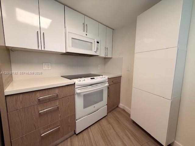 A kitchen features white upper cabinets, wood-tone lower cabinets, and stainless steel appliances — 2415 NW 16th St Rd # 1, Miami FL 33125, MIAMI, FL