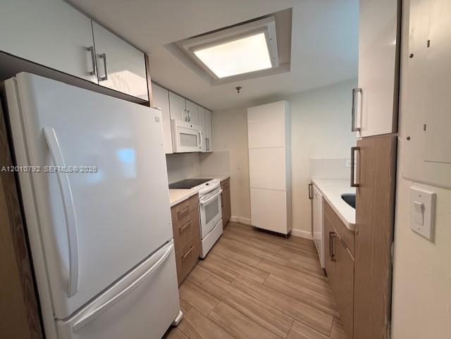 A kitchen features white cabinets, a white refrigerator, and light wood-look flooring — 2415 NW 16th St Rd # 1, Miami FL 33125, MIAMI, FL