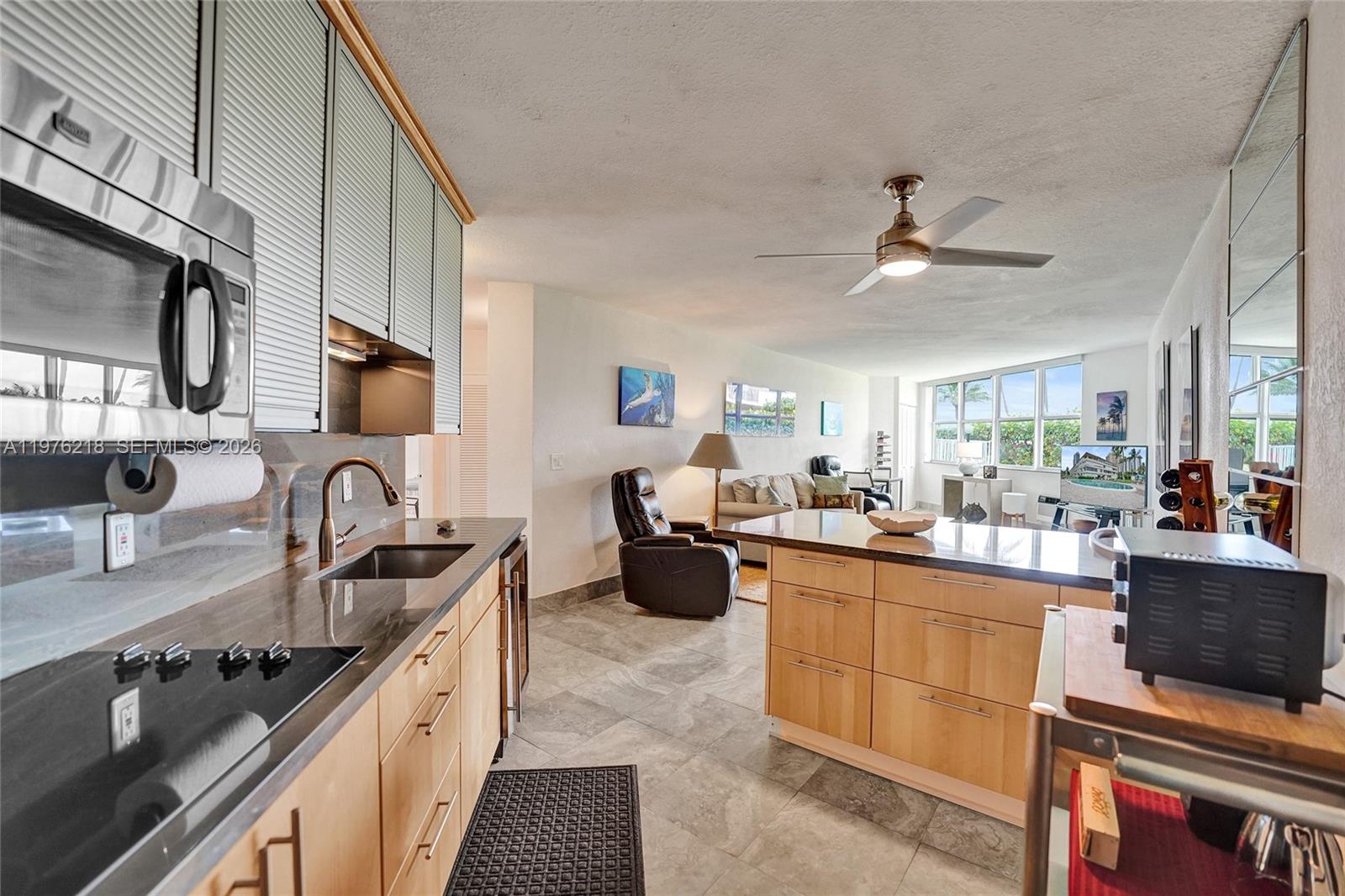 A kitchen with light wood cabinets and dark countertops opens into a living area — 1936 S Ocean # 20D, Hallandale Beach FL 33009, HALLANDALE BEACH, FL