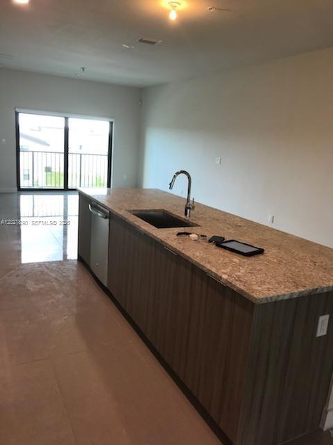 A kitchen island with a sink and stone countertop sits in a room with tile flooring — 7805 NW 104 Ave # 31, Doral FL 33178, DORAL, FL