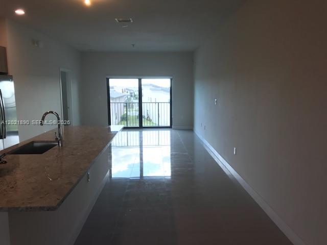 A kitchen island with a granite countertop overlooks an open living area with sliding doors — 7805 NW 104 Ave # 31, Doral FL 33178, DORAL, FL