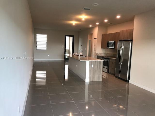 An open-concept kitchen features a central island, stainless steel appliances, and glossy tile flooring — 7805 NW 104 Ave # 31, Doral FL 33178, DORAL, FL