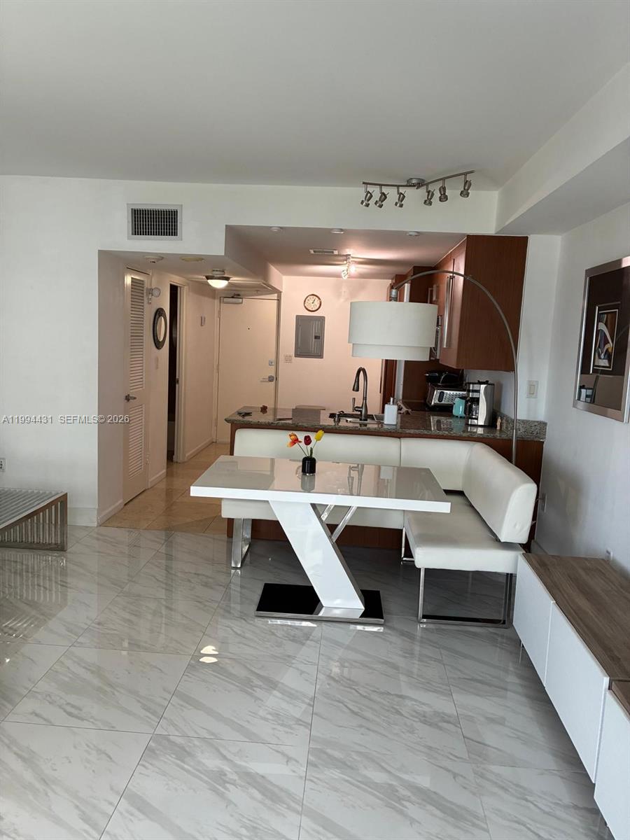 A modern dining area features a white corner bench, a glossy table, and marble-look flooring — 10275 Collins Ave # 1004, Bal Harbour FL 33154, BAL HARBOUR, FL