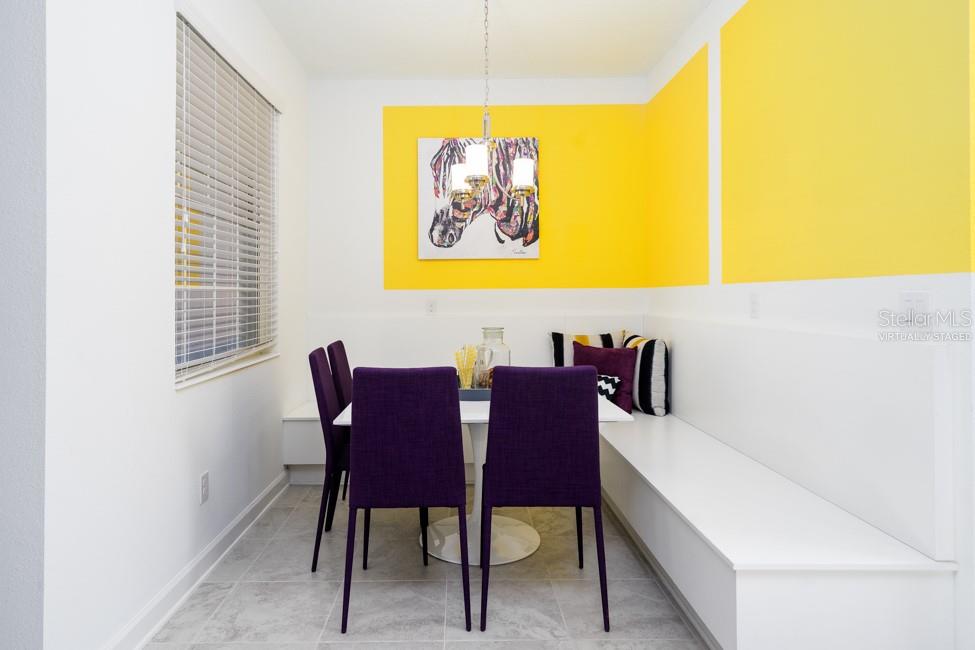 A dining nook features a white built-in bench, purple chairs, and yellow wall accents — 6045 MEDITATION DRIVE, CLERMONT, FL
