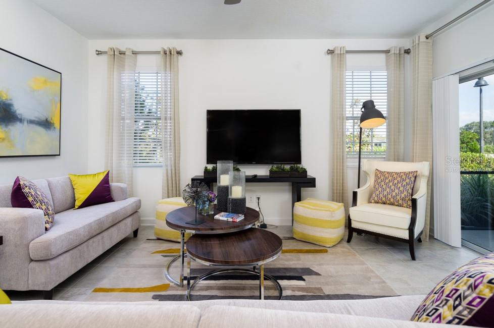 A living room features a sofa, armchair, nested coffee tables, and a television on a console — 6045 MEDITATION DRIVE, CLERMONT, FL