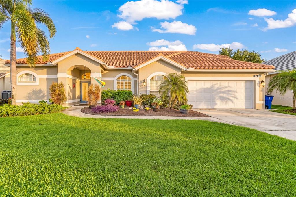 A single-story house with a tile roof, a two-car garage, and a landscaped front yard — 12808 VISTA PINE CIRCLE, FORT MYERS, FL