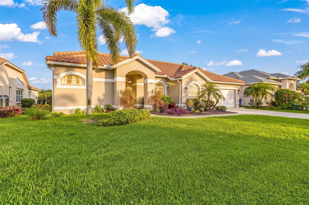 A single-story suburban house with a tile roof, palm tree, and green lawn — 12808 VISTA PINE CIRCLE, FORT MYERS, FL