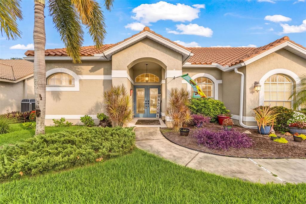 A single-story house with a beige stucco exterior, tile roof, and a blue double-door entrance — 12808 VISTA PINE CIRCLE, FORT MYERS, FL