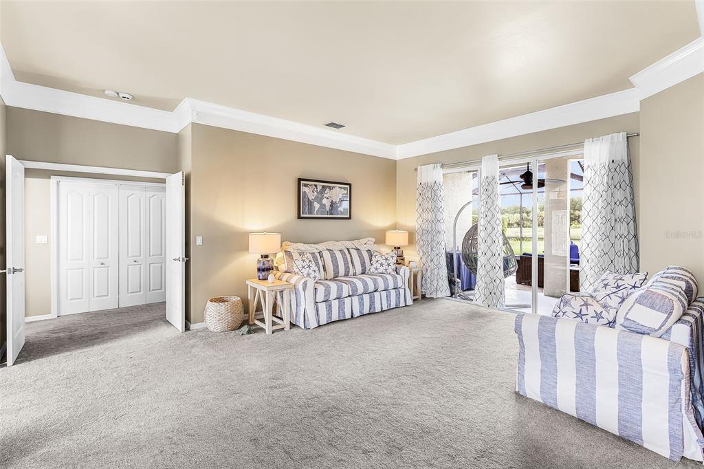 A living room with beige walls, carpeted flooring, striped furniture, and sliding glass doors to a patio — 12808 VISTA PINE CIRCLE, FORT MYERS, FL