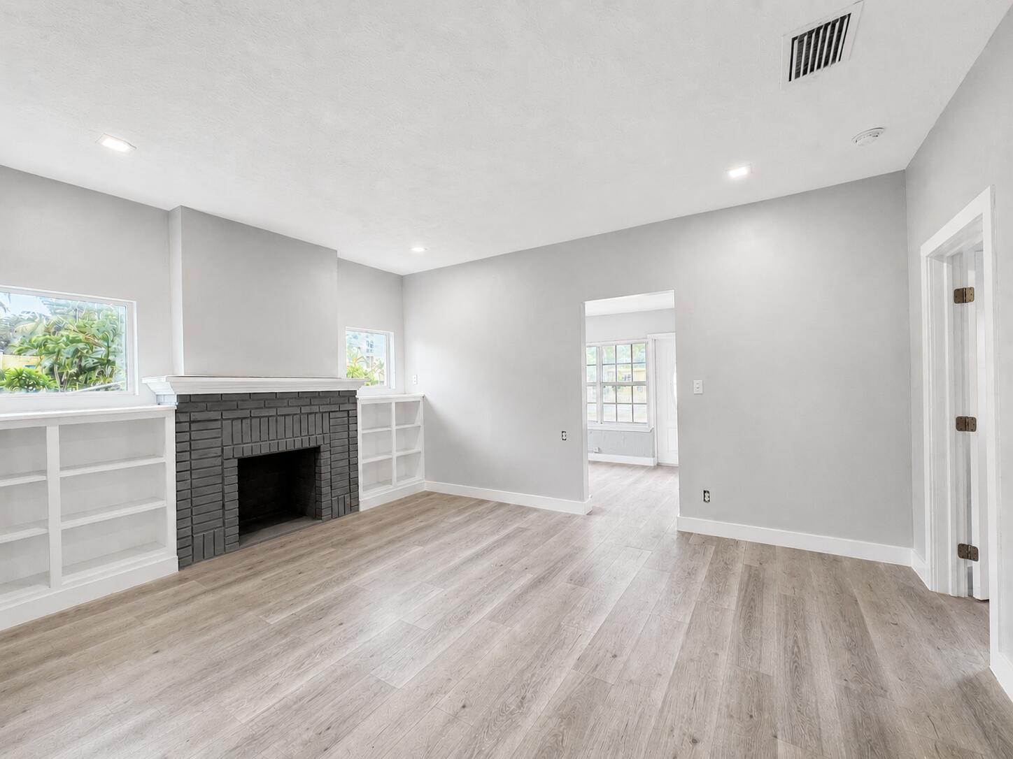A living room features light gray walls, wood-look flooring, a dark brick fireplace, and built-in shelves — 1905 Monroe Street, Hollywood FL 33020, HOLLYWOOD, FL