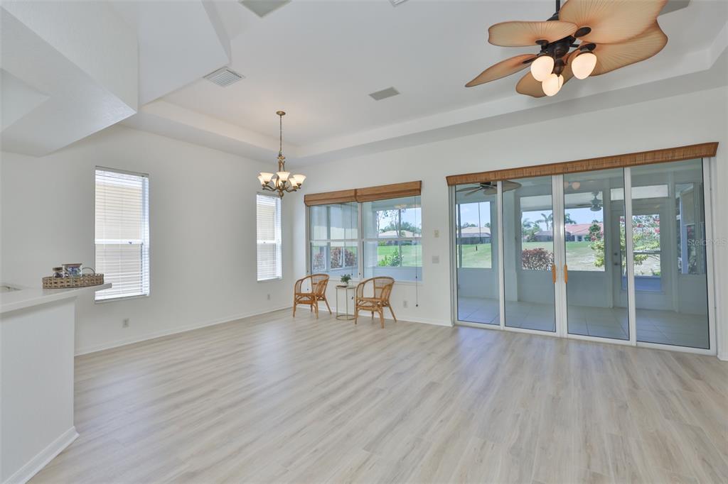 A bright living area features light wood-look flooring, a ceiling fan, and sliding glass doors — 448 NOBLE FAIRE DRIVE, SUN CITY CENTER, FL