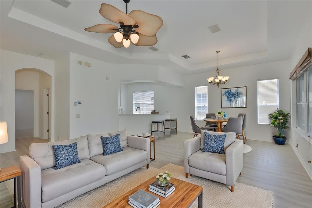 A living room and dining area feature light flooring, neutral furniture, and a ceiling fan — 448 NOBLE FAIRE DRIVE, SUN CITY CENTER, FL