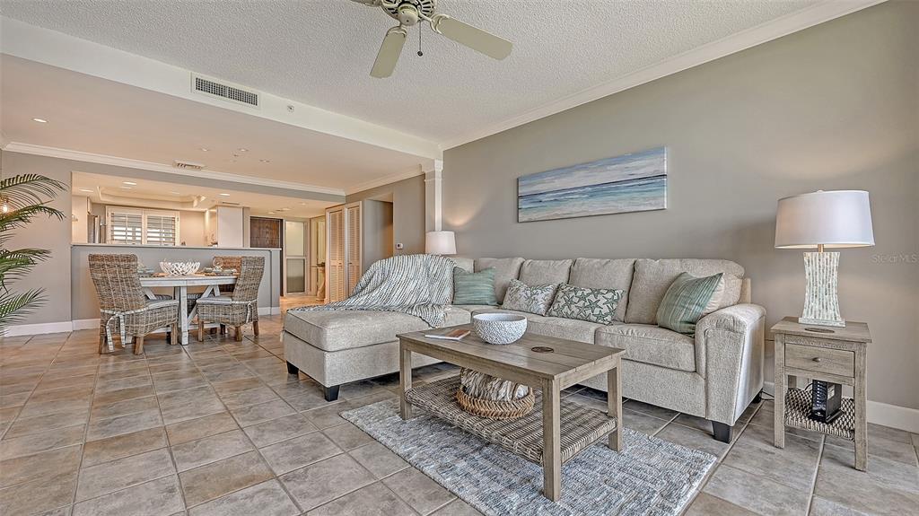A living room with a sectional sofa, coffee table, and dining area on tiled floors — 2109 GULF OF MEXICO DRIVE UNIT 1203, LONGBOAT KEY, FL