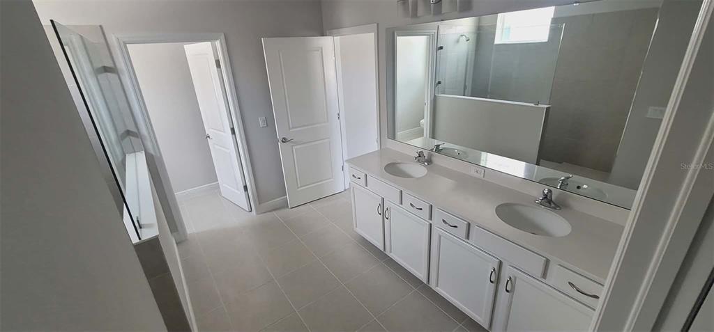 A bathroom features a double vanity with white cabinets, a large mirror, and tiled flooring — 9273 HIGHLAND HILLS DRIVE, HUDSON, FL