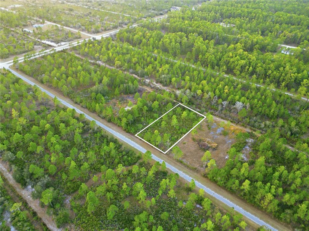 An aerial view shows a rectangular plot of land outlined in white amidst wooded terrain — 310 TROPICANA DRIVE, INDIAN LAKE ESTATES, FL