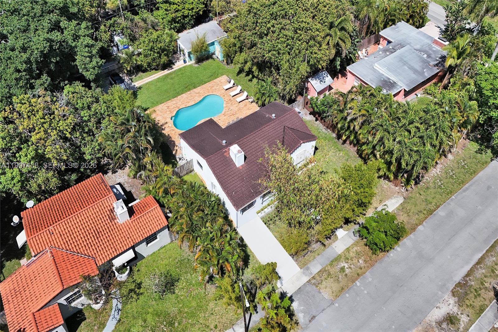 An aerial view shows a house with a brown roof, a pool, and surrounding trees — 1515 Dewey St, Hollywood FL 33020, HOLLYWOOD, FL