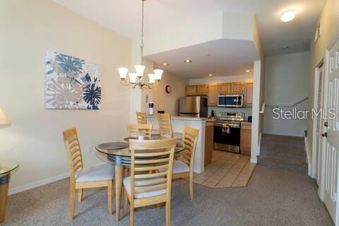 A dining area with a glass-topped table and chairs sits adjacent to an open kitchen — 4011 VENETIAN BAY DRIVE UNIT 106, KISSIMMEE, FL