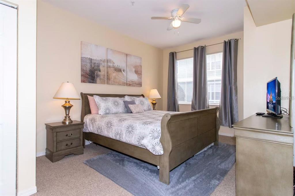 A bedroom features a wooden sleigh bed, two nightstands with lamps, and a television dresser — 4011 VENETIAN BAY DRIVE UNIT 106, KISSIMMEE, FL