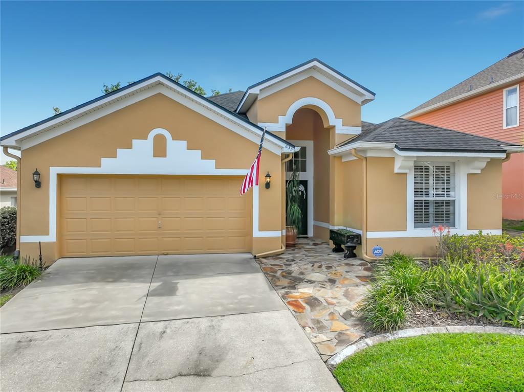 A single-story house with a tan stucco exterior, a two-car garage, and a stone walkway — 233 HANGING MOSS CIRCLE, LAKE MARY, FL
