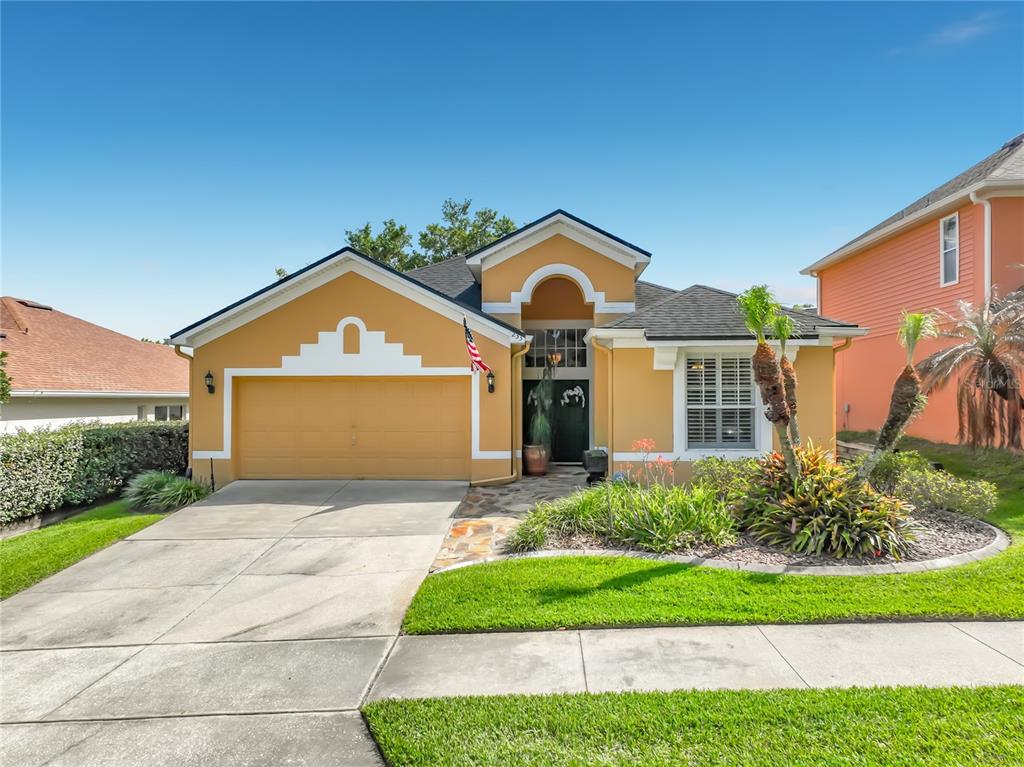 A single-story yellow house with a two-car garage and a stone walkway — 233 HANGING MOSS CIRCLE, LAKE MARY, FL