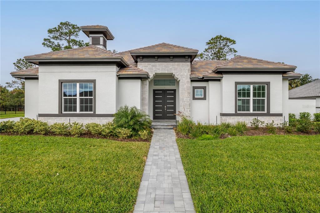A single-story house with a stone-accented entryway, dark-framed windows, and a paved walkway — 109 NEW LEATHERWOOD DRIVE, PALM COAST, FL