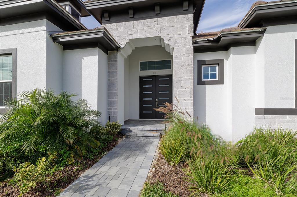 A stone-accented entryway features a double front door with horizontal glass panels and a walkway — 109 NEW LEATHERWOOD DRIVE, PALM COAST, FL