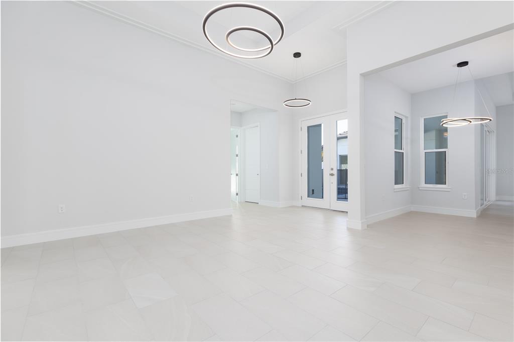 An empty room with white walls, light tile flooring, and modern circular pendant lighting — 109 NEW LEATHERWOOD DRIVE, PALM COAST, FL