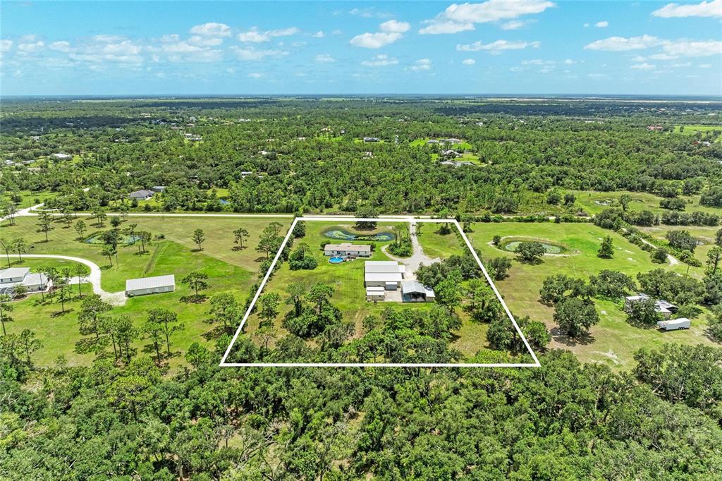 A large metal workshop building with a concrete driveway and an attached carport — 23715 73RD AVENUE E, MYAKKA CITY, FL