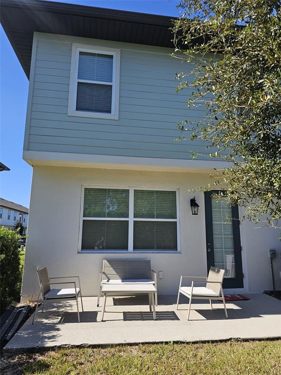 A patio with a small table and three chairs sits outside a two-story house — 1457 DISCOVERY STREET, DAVENPORT, FL