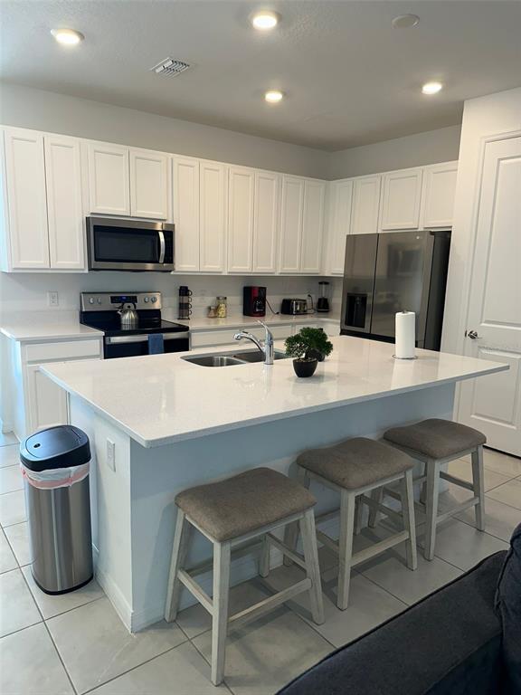 A modern kitchen features white cabinets, stainless steel appliances, and a large central island — 1457 DISCOVERY STREET, DAVENPORT, FL