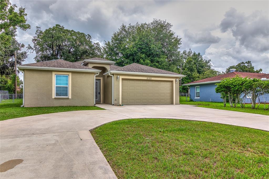 A single-story tan stucco house with a two-car garage and a concrete driveway — 5130 20TH STREET, ZEPHYRHILLS, FL